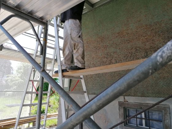 Ansicht der Baustelle mit Gerüst und Planen auf dem Bauernhof