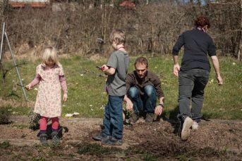 Mutter und Vater spielen gemeinsam mit den beiden Kindern draussen.