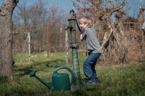Junge füllt die Giesskanne im Garten.