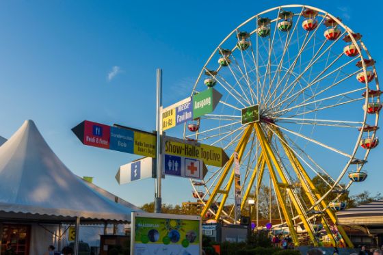 Gelbes Riesenrad im Vordergund und Zelte im Hintergrund