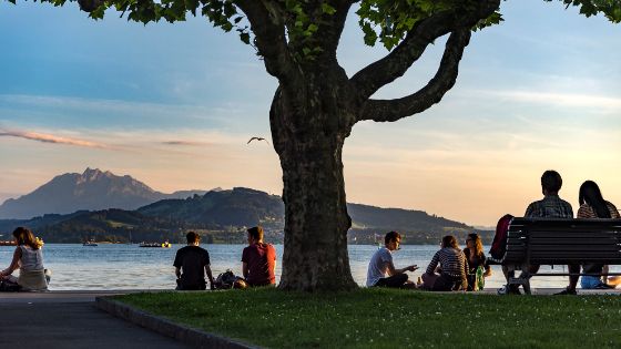 Personen sitzen am Ufer des Zugersees bei Sonnenuntergang