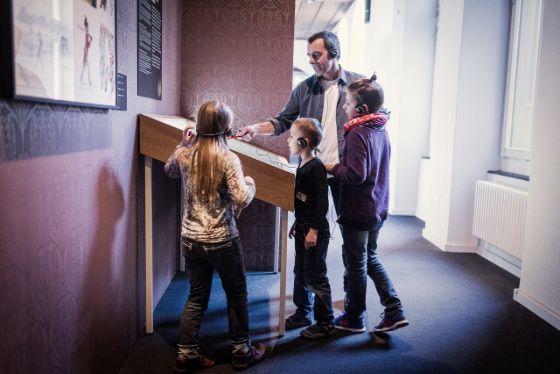 Mann mit drei Kindern in einem Museum.